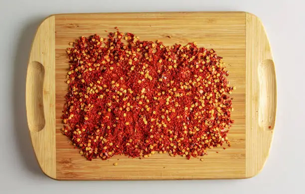 Photo of Dried red pepper powder. Background of crushed dry chili peppers on a wooden board.