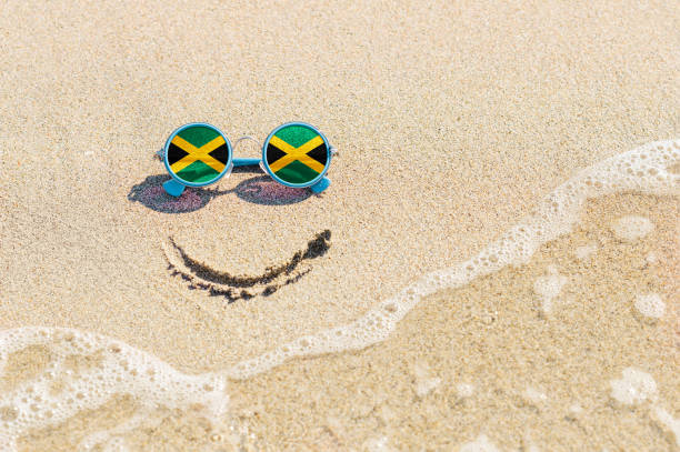 un sourire peint sur le sable et des lunettes de soleil avec le drapeau de la jamaïque. - jamaican culture photos et images de collection