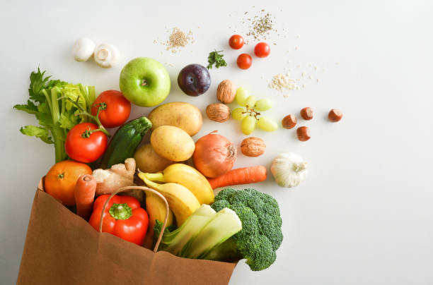 sac à provisions recyclable avec fruits et légumes sur table blanche - simple food photos et images de collection