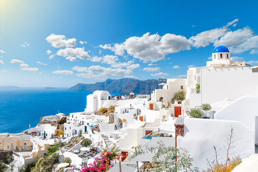 View from a whitewashed terrace of the caldera, sea and village of Oia, Santorini, Greece, with one of the famous blue dome churches in view.
