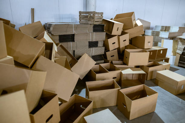 istock Assembled and disassembled folding cardboard boxes of perforated sheets of corrugated cardboard. Packaging of finished products in industrial production. 1369835098