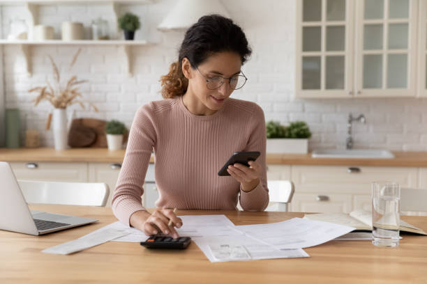 istock Young woman calculate expenses paying on cell online 1369837665