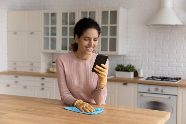 istock Happy Caucasian housewife clean kitchen using cellphone 1369837933