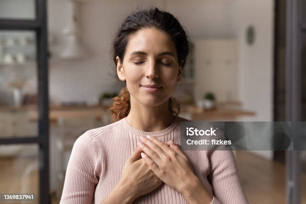 Calm Young Woman Hold Hands On Chest Praying Stock Photo - Download Image Now - Mental Health, Healthy Lifestyle, Healthcare And Medicine