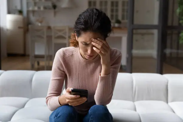 Photo of Unhappy woman use smartphone distressed with bad news