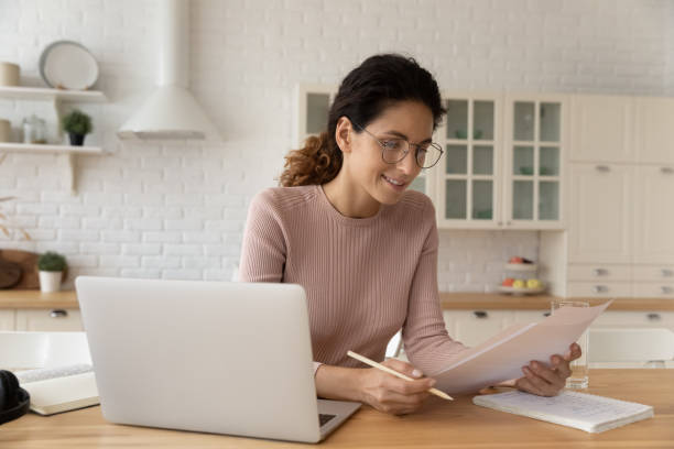 istock Smiling Caucasian woman work with documents at home office 1369838488