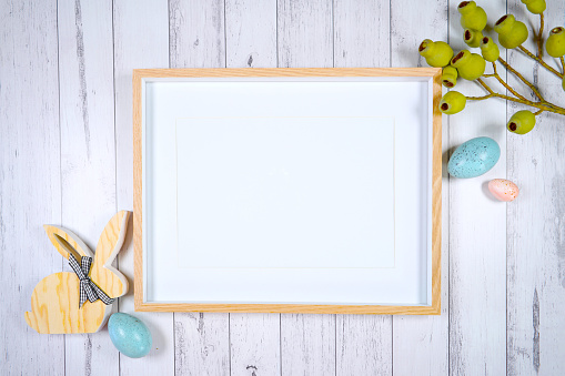 Horizontal picture frame mockup. Happy Easter farmhouse theme SVG craft product mockup styled with wooden bunnies and pastel eggs against a white wood background.
