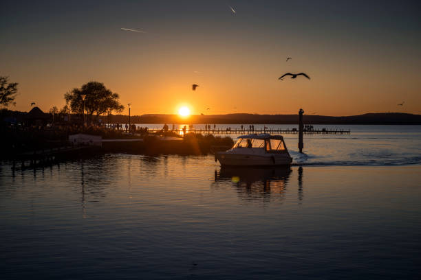 bateau à moteur et jetée dans le steinhuder meer au coucher du soleil - steinhuder meer photos et images de collection