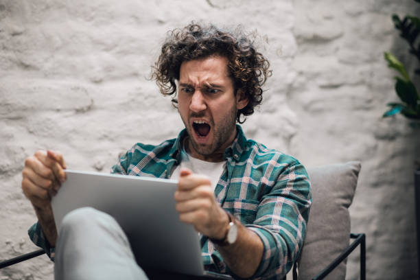 Shocked. Shot of an attractive young businessman sitting alone in his office and feeling stressed stock photo