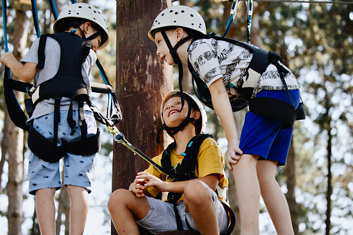 Children wearing safety equipment carabiner and ropes for climbing trees in extreme park