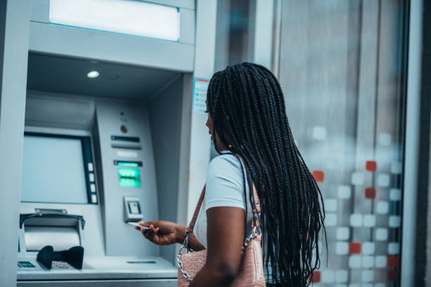 jeune femme afro-américaine utilisant une carte de crédit et un distributeur automatique de billets - guichet automatique de banque photos et images de collection