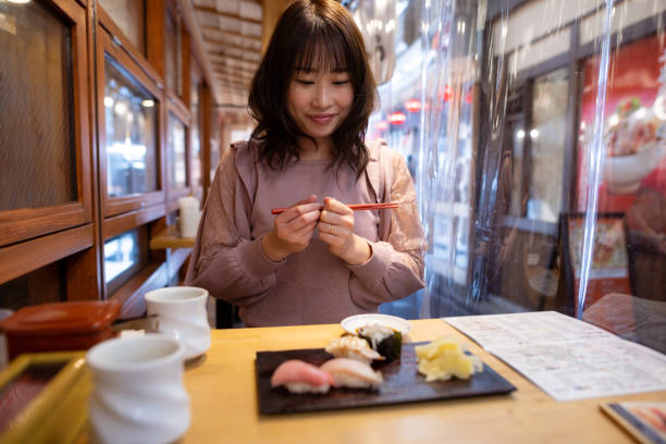 Woman eating sushi for lunch at outdoor restaurant stock photo