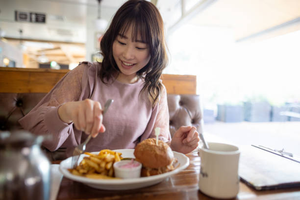 istock Woman eating hamburger for lunch at restaurant 1369855593