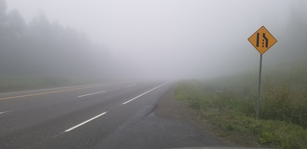 Early morning highway covered in thick dense fog.