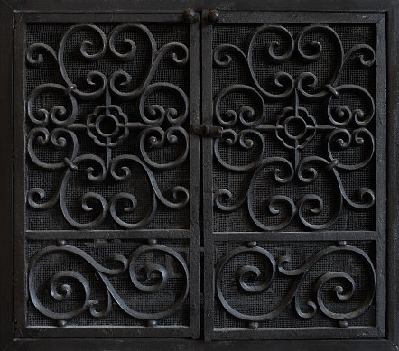 Black ornate door on hinges, opening in the middle.