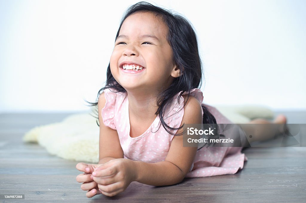 Smiling Little Girl Little Girl smiling happy laying on the floor Asian and Indian Ethnicities Stock Photo