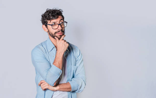 istock young man wondering with his hand on his chin on an isolated background, a guy thinking with his hand on his chin. 1369887952