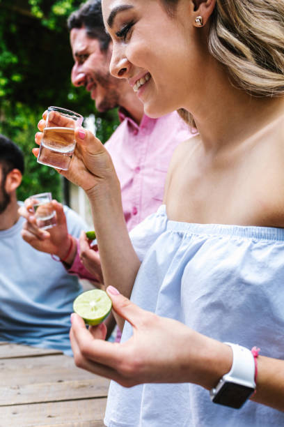 tequila shot, réunion d’un groupe de jeunes amis latins pour des boissons à la tequila ou au mezcal faire un toast à la terrasse du restaurant au mexique amérique latine - tequila frappée photos et images de collection