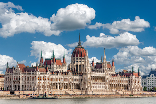 Diagonal view of the exterior façade of the Hungarian Parliament building in Budapest on the Danube with blue sky and fair-weather clouds