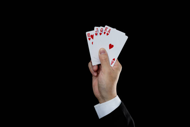 黒い背景に王室のフラッシュを保持するビジネスマンの手 - poker cards royal flush leisure games ストックフォトと画像