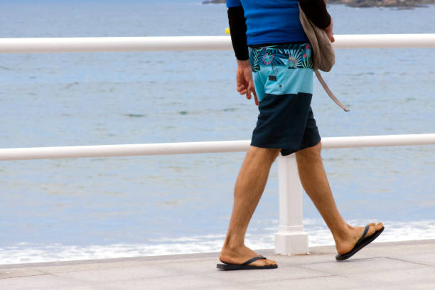 Young man walking on the sidewalk by the beach. stock photo