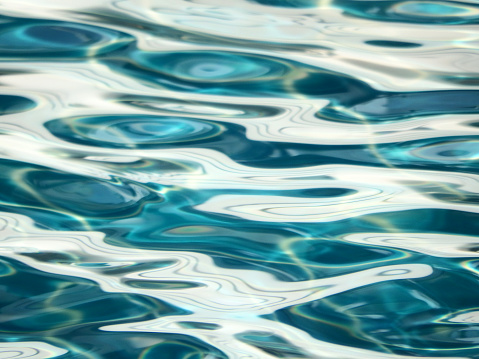 Abstract water ripples background with close up details of cool blue pools of water and white patterns from sunlight reflections on the water's surface