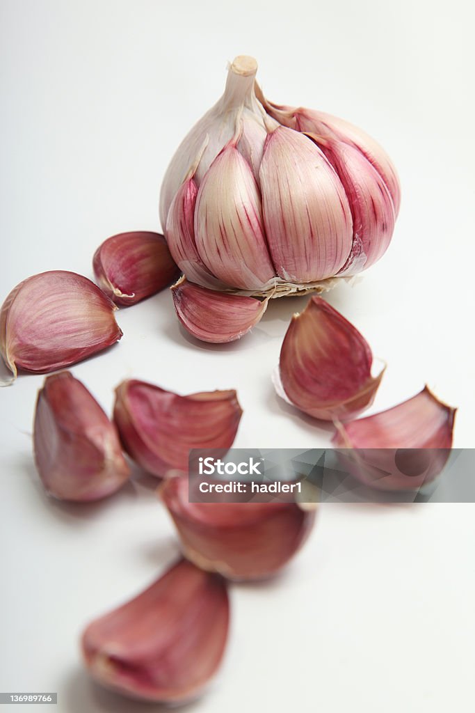 Raw Garlic Garlic cloves peeled and scattered on a white background.  Focus on the whole bulb at the back Food Stock Photo