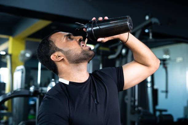 istock bodybuilder drinking or taking protein powder and mixing with water on bottle by shaking at gym - concpet of muscular gain, fitness training and workout 1369897745