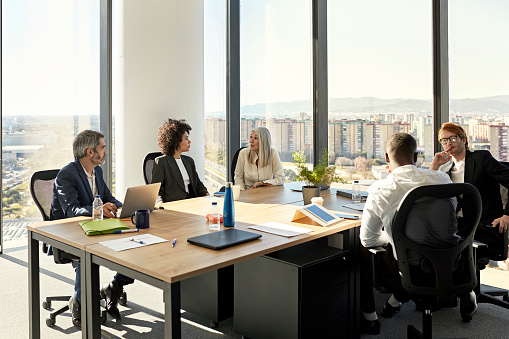 Full length view of mixed age range group of colleagues in businesswear sitting together and exchanging ideas.