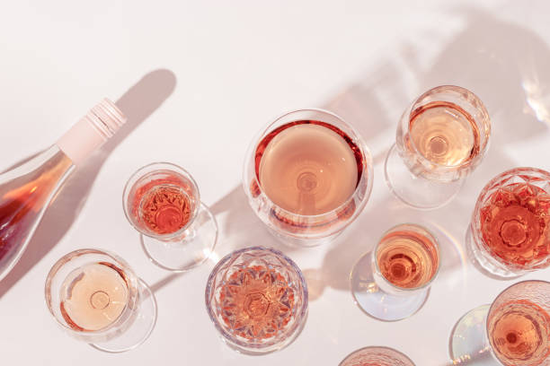 Many glasses of rose wine and bottle sparkling pink wine top view. Light alcohol drink for party. Many glasses of rose wine and bottle sparkling pink wine top view. Light alcohol drink for party. Flat lay on light table at summer day with shadows. rose wine stock pictures, royalty-free photos & images