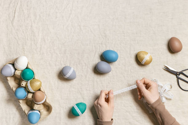 istock Decoration colored Easter eggs, prepare for Happy Easter celebration, woman decorating dyed chicken egg with tape lace on table linen Lifestyle aesthetic photo at home, diy holiday 1369903199