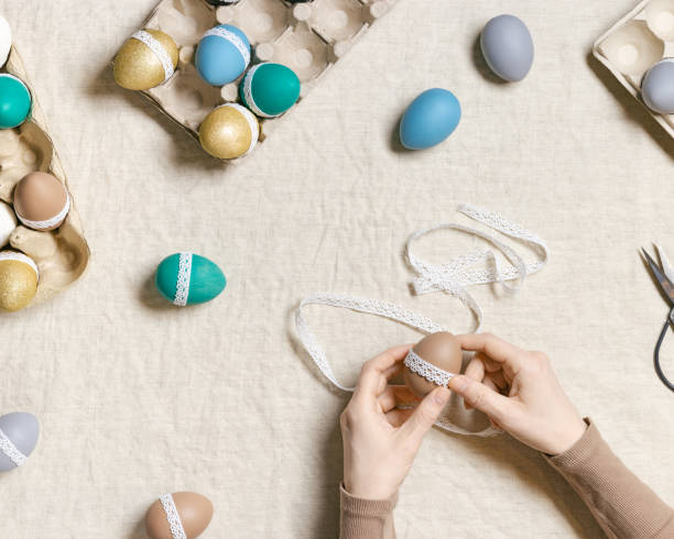 istock Decoration colored Easter eggs, prepare for Happy Easter celebration, woman decorating dyed chicken egg with tape lace on table linen Lifestyle aesthetic photo at home, diy holiday 1369903201