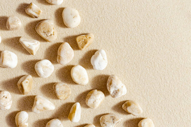 istock Aesthetic minimal pattern with pebble stones on fine sand background. Top view on natural stone neutral yellow beige pastel colored image 1369903281