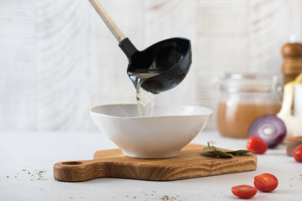 A ladle is poured with a healthy homemade bone broth into a plate.