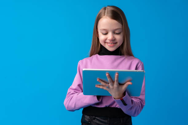istock Little girl uses a digital tablet on a blue background 1369908445