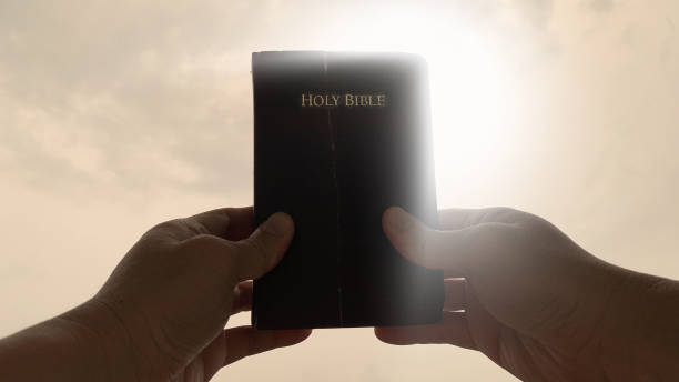 istock Hand holding an old Holy Bible with shining light background. Christian concept. 1369909944