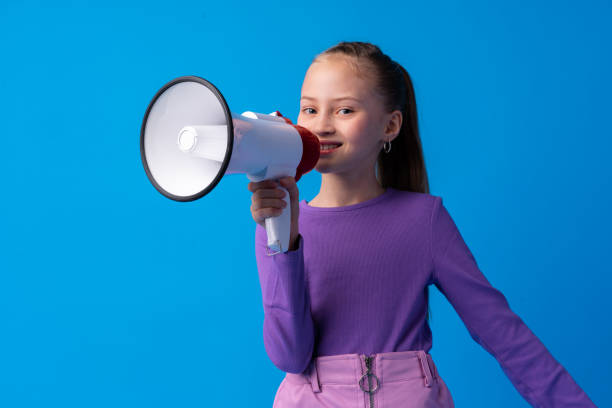 istock Child girl using megaphone against blue background 1369910219