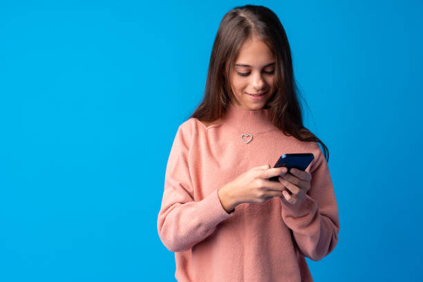 portret nastoletniej młodej dziewczyny używającej smartfona na niebieskim tle - telephone child isolated on white elegance zdjęcia i obrazy z banku zdjęć