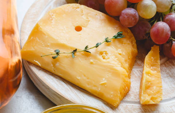 cheddar cheese with grapes, pink wine, honey. wine cheese snacks for a romantic dinner. aged dutch gouda cheese on cheeseboard with cumin herbs on table. - gouda imagens e fotografias de stock