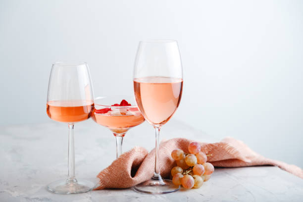 istock Rose wine in different types of glasses on light grey concrete background with grapes. Rose Wine composition on white table. 1369911618