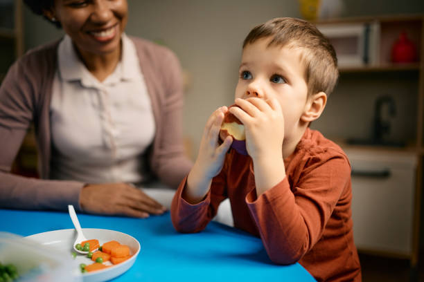 istock Little boy having an apple for a snack at kindergarten. 1369912958