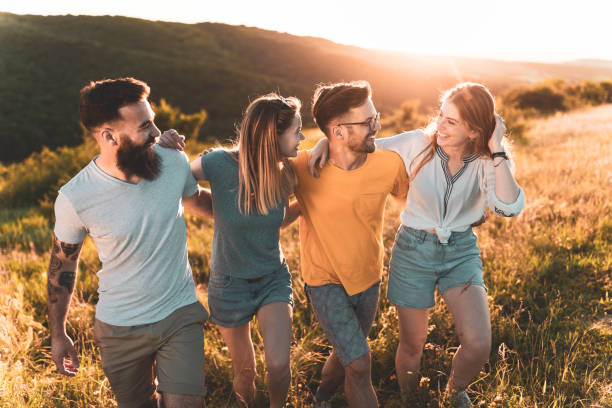 istock Happy embraced friends talking and walking on a hill at sunset. 1369913060
