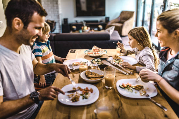 istock Happy family enjoying while having lunch in dining room. 1369913911