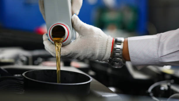 Auto mechanic in gloves pour engine oil into engine Auto mechanic in gloves pour engine oil into engine. Changing oil in car concept food additive stock pictures, royalty-free photos & images