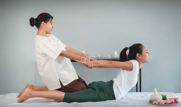 Woman is receiving Back Massage Stretching in Thai Therapy Spa treament. stock photo