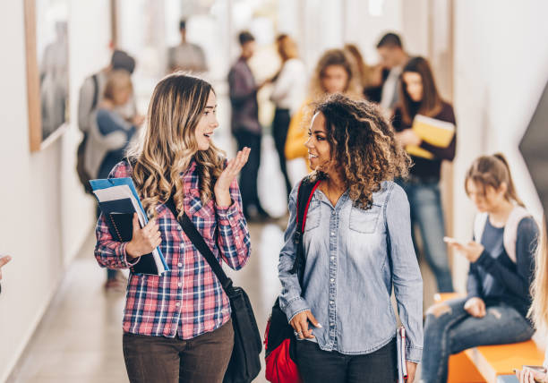 istock Happy college friends communicating while walking through hallway. 1369917298