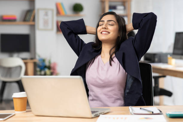 junge frau im büro, die am laptop arbeitet. stockfoto - hände hinter dem kopf stock-fotos und bilder