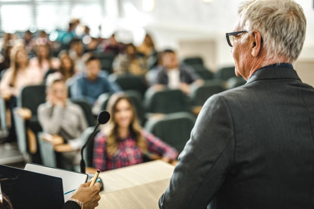 istock Rear view of mature professor teaching his students in a lecture hall. 1369917406