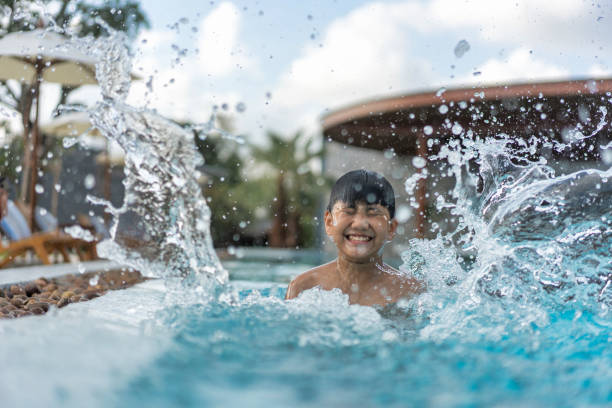 asian young boy having a good time in swimming pool, he jumping and playing a water in summer. - blue water swimming pool sports and fitness imagens e fotografias de stock