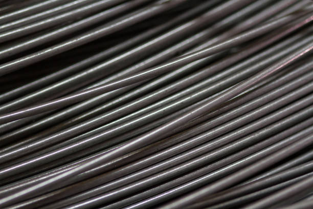 istock Stainless steel wire in production workshop or construction site. Close-up of wire rollers for spring production or concrete reinforcement. Metal texture. Industrial or construction concept. 1369919606